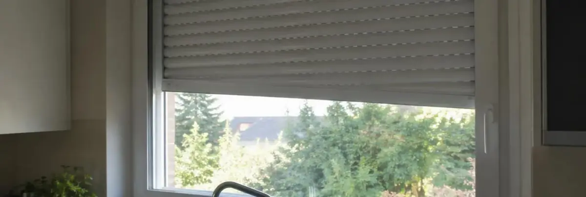 Volet roulant blanc arrêté de travers aux deux tiers de sa course, vu de l'intérieur d'une cuisine